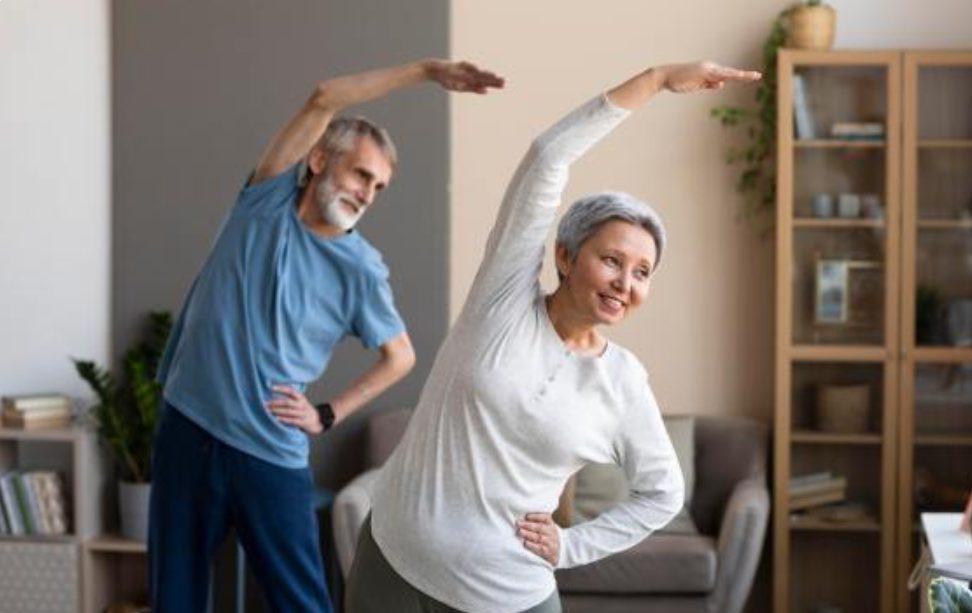 Dos personas maduras haciendo ejercicio físico en casa.